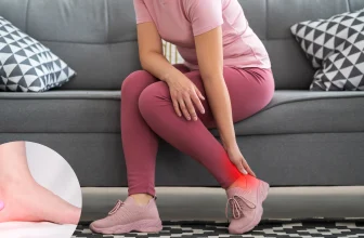 Femme assise sur un canapé tenant son talon avec une douleur visible, suggérant une épine calcanéenne ou une autre affection du pied.